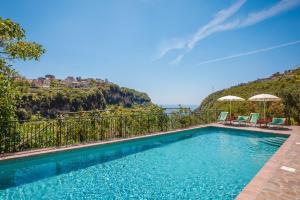 a swimming pool with chairs and umbrellas in front of a mountain at Villa san Lorenzo rooms in Scala