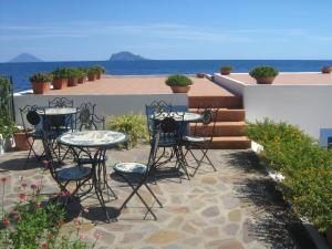 a patio with tables and chairs and the ocean at Hotel Punta Barone in Santa Marina Salina