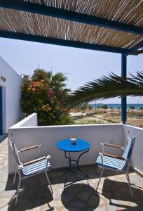 a patio with two chairs and a blue table at Sardis Rooms in Kimolos