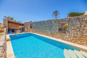 a swimming pool in front of a stone wall at La font in Pollença