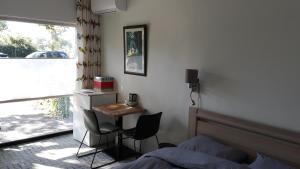 een slaapkamer met een bed, een bureau en een raam bij Biesbosch Bed & Breakfast Werkendam in Werkendam