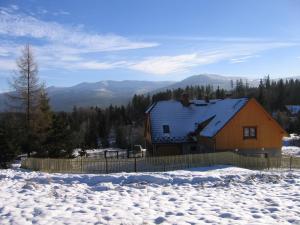 ein Haus im Schnee mit Bergen im Hintergrund in der Unterkunft Willa Marzenie in Szklarska Poręba