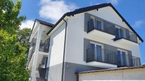 a white building with black shutters on it at Plażowe Apartamenty Grzybowo in Grzybowo