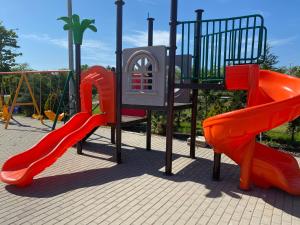 a playground with two red slides and a play structure at Resort Plaza Lake in Rojiştea
