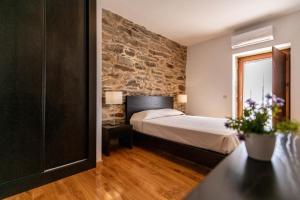 a bedroom with a bed and a stone wall at Terraços de Baco in Ribalonga