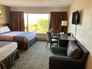 a hotel room with two beds and a desk at Knights Inn Kamloops in Kamloops