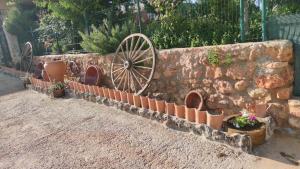 a stone wall with potted plants and a wooden wheel at El Retiro de Cervantes in Ossa de Montiel
