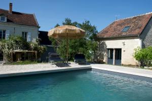 a swimming pool with an umbrella and a house at Maison Saint Georges in Saint-Georges-sur-Cher