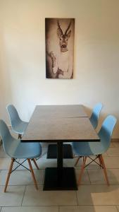 una mesa con sillas azules y una foto de un ciervo en Pineapple Apartments Dresdner Heide mit Garten, en Dresden