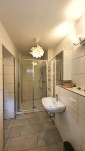 y baño blanco con lavabo y ducha. en Pineapple Apartments Dresdner Heide mit Garten, en Dresden