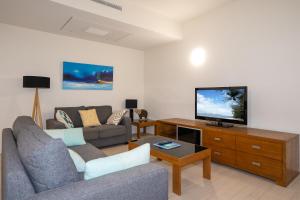 a living room with a couch and a tv at Elysium The Drift in Palm Cove