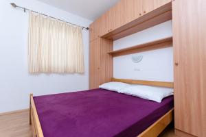 a bedroom with a purple bed and a window at Apartments Alex in Lopar