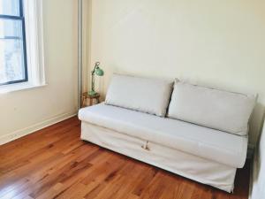 a white couch in a room with a window at 2 Bedrooms Entire Beautiful Apt in Williamsburg! in Brooklyn