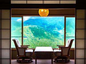 een kamer met een tafel en stoelen en een groot raam bij Shirayunoyado Yamadaya Hakone Gora in Hakone