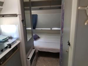 ソゾポルにあるCaravan Sozopolの小さなベッドと鏡が備わる小さな客室です。