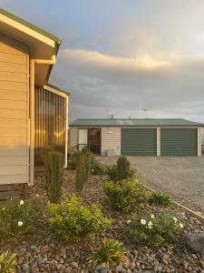 a house with green garage doors and a gravel driveway at Chris and Dave's B & B in Otorohanga