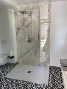 a bathroom with a shower with a glass door at Cocon en lisière de forêt in Bourron-Marlotte
