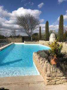 a large swimming pool with a stone retaining wall and anergynergynergynergynergy at Le Bastidon de L Olivier in Gordes