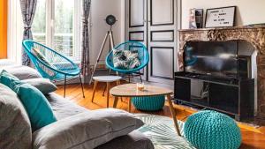ein Wohnzimmer mit einem Sofa, Stühlen und einem TV in der Unterkunft Cosy'Appart - LE BOUQUET in Rouen