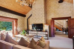 a living room with a couch and a tv at Villa Casa Maria Luxury Farmhouse in Katikati