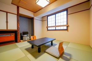 um quarto com uma mesa, uma cadeira e uma televisão em Ryokan Wakamiya em Quioto
