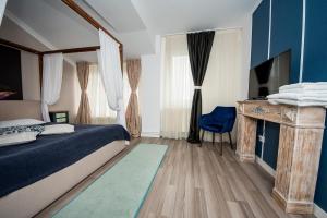 a bedroom with a bed and a television and a table at Hotel Jolie Apartments in Galaţi +162 photos
