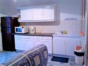 ラ・ブルブールにあるDoux Ombragesの白いキャビネット、シンク、電子レンジ付きのキッチンが備わります。