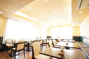 un restaurante con mesas y sillas y una gran ventana en ホテル大藏, en Kanoya