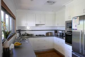a white kitchen with white cabinets and white appliances at A Market Place Mudgee in Mudgee