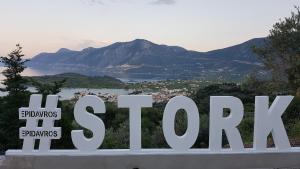 a sign that reads stay open with a mountain in the background at STORK Design Suites in Ancient Epidauros