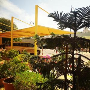 una tienda amarilla en un estacionamiento con plantas en Bowshar International Hotel, en Mascate