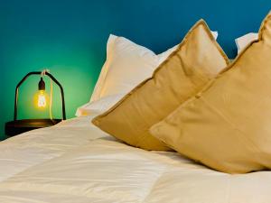 Una cama blanca con almohadas y una lámpara en una mesa. en Crops City Stay en Trieste