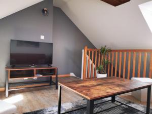 Una sala de estar con una mesa y un televisor. en L'Ancre Marine, en Cancale
