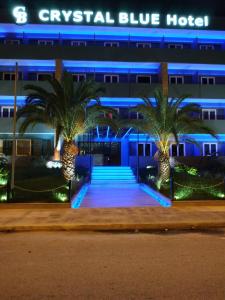 un hôtel bleu avec des palmiers devant lui dans l'établissement THE CRYSTAL BLUE XAIDARI HOTEL, au Pirée