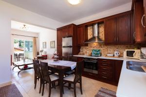 a kitchen with wooden cabinets and a table with chairs at Andi Vacation Home in Lefkogeia