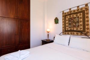 1 dormitorio con cama blanca y armario de madera en Andi Vacation Home, en Lefkogeia