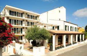 un grand bâtiment blanc avec un arbre en face dans l'établissement Hotel Angedras, à Alghero