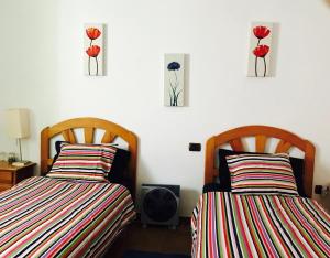 - 2 lits dans une chambre avec des fleurs rouges sur le mur dans l'établissement WIFI TENERIFE SUR GUEST HOUSE, à Granadilla de Abona