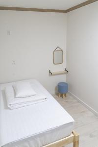 Habitación blanca con cama y silla azul en Hwarang Guesthouse en Gyeongju