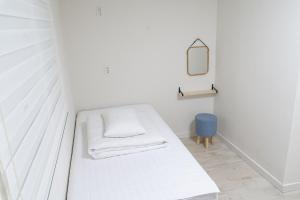 Habitación blanca con cama y espejo en Hwarang Guesthouse, en Gyeongju