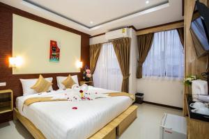 a bedroom with a large white bed with flowers on it at OYO 996 Phunara Residence in Patong Beach