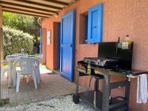 um pátio exterior com comodidades para churrascos, uma mesa e portas azuis em Mas Rose des Vents em Le Barcarès