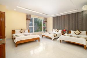 Cette chambre comprend 3 lits et une fenêtre. dans l'établissement Khách sạn Đàm Phúc Đà Nẵng, à Đà Nẵng