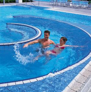 
a man and a boy swimming in a pool at Hotel Fortuna in Bad Gögging
