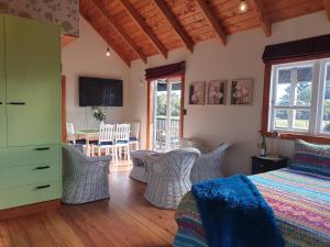 a bedroom with a bed and chairs and a table at The Blackhouse Cottage in Hokitika