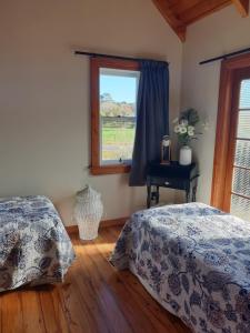 een slaapkamer met 2 bedden en een raam bij The Blackhouse Cottage in Hokitika