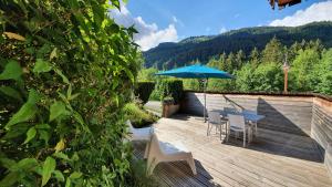 una terraza de madera con mesa, sillas y sombrilla en La Duche 101, en Le Grand-Bornand