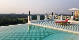a swimming pool with two chairs and an umbrella on a building at The Glenburn Penthouse in Kolkata
