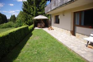 a garden with a bench and an umbrella next to a house at Ferienwohnung " MILA" in Schwarzwald near Titisee in Oberbränd