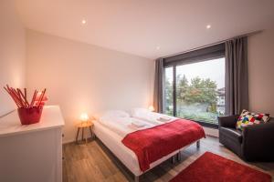 1 dormitorio con 1 cama, 1 silla y 1 ventana en Independance Penthouse en Interlaken